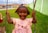 A happy child wearing a colorful school dress, smiling in a playground.