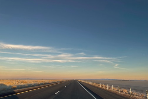 A wide shot of a perimeter fence stretching along a desert road in Qatar during sunset.