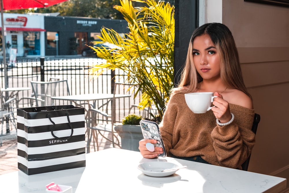 a woman sitting at a table with a cup of coffee