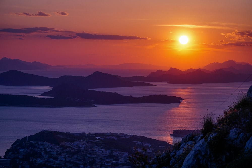 a sunset over a body of water with mountains in the background