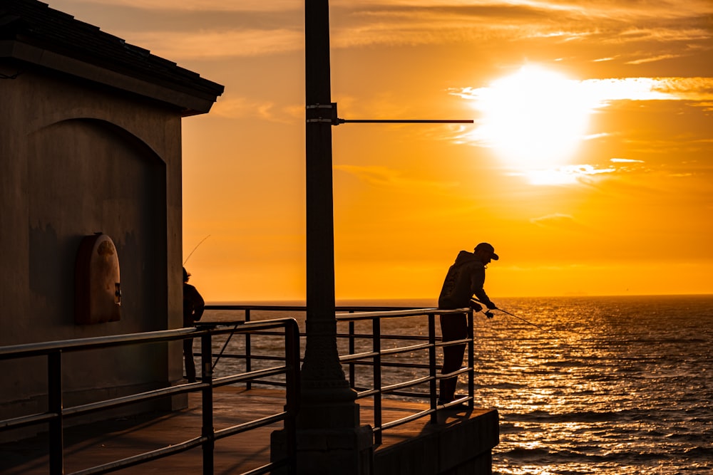 a man standing on a pier next to the ocean