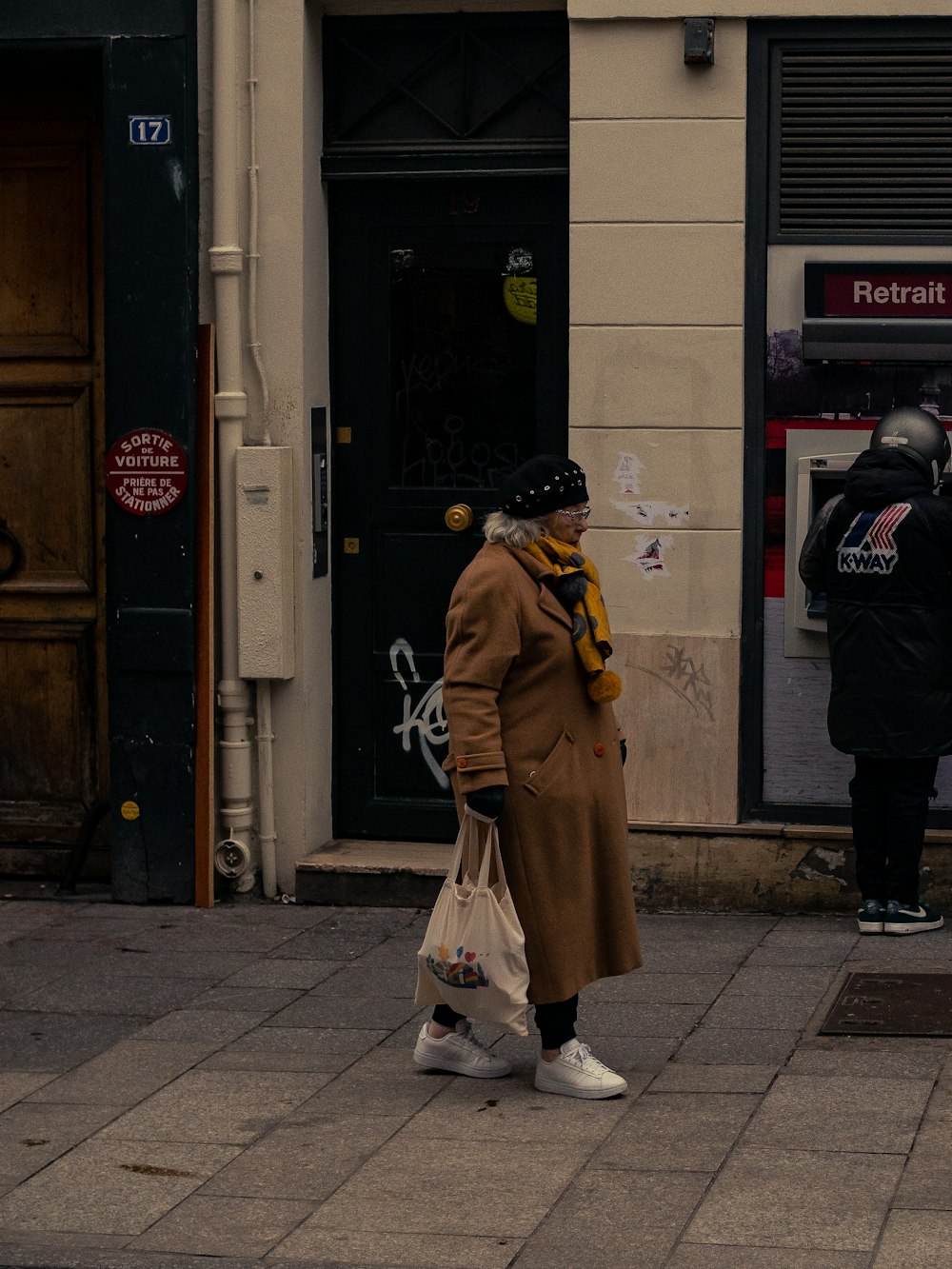 a woman walking down a sidewalk carrying a bag