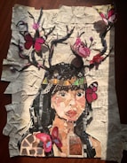 A collage depicting a woman's face made from various pieces of paper on a background of crumpled, printed sheets. Branches extend from her head with vibrant pink and red butterflies perched on them. The overall effect combines elements of nature and art in a visually engaging manner.