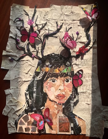 A collage depicting a woman's face made from various pieces of paper on a background of crumpled, printed sheets. Branches extend from her head with vibrant pink and red butterflies perched on them. The overall effect combines elements of nature and art in a visually engaging manner.