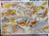 Watercolor painting of numerous goldfish swimming gracefully in different directions. Their scales glisten in hues of gold, orange, and red, with delicate brush strokes capturing the fluidity of their movement against a pale, abstract background.