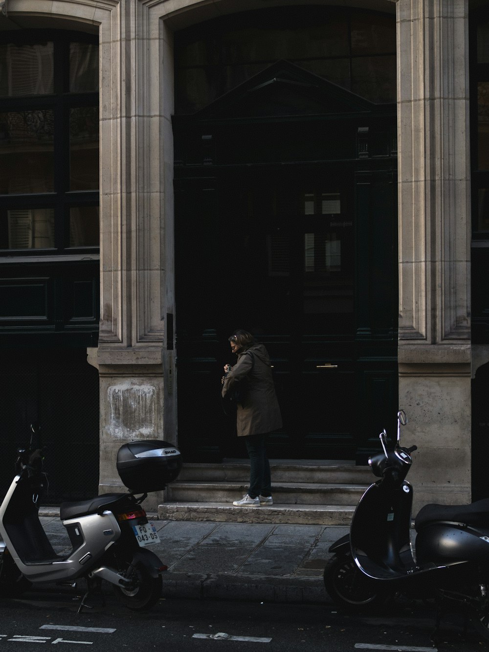 a man standing in front of a building next to scooters