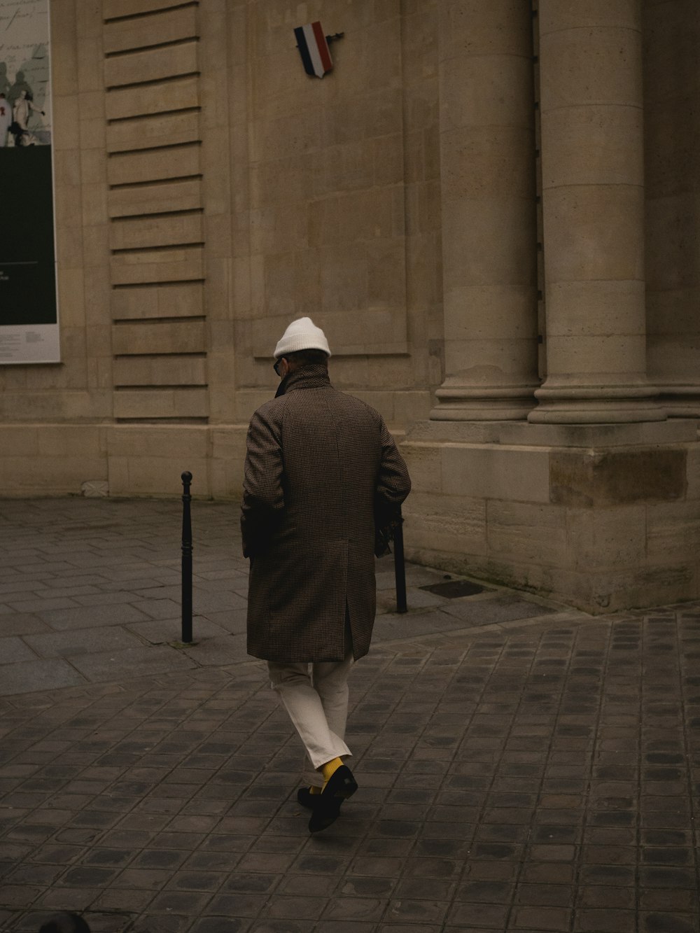 a man walking down the street in a coat and hat