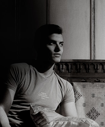 a black and white photo of a man sitting on a couch