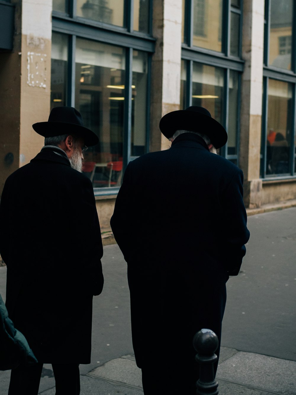 Deux hommes debout sur un trottoir devant un immeuble