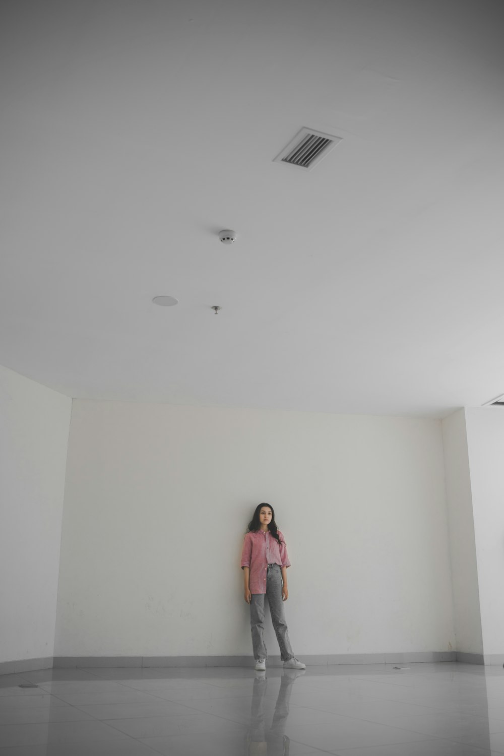 a woman standing in a room with a white wall