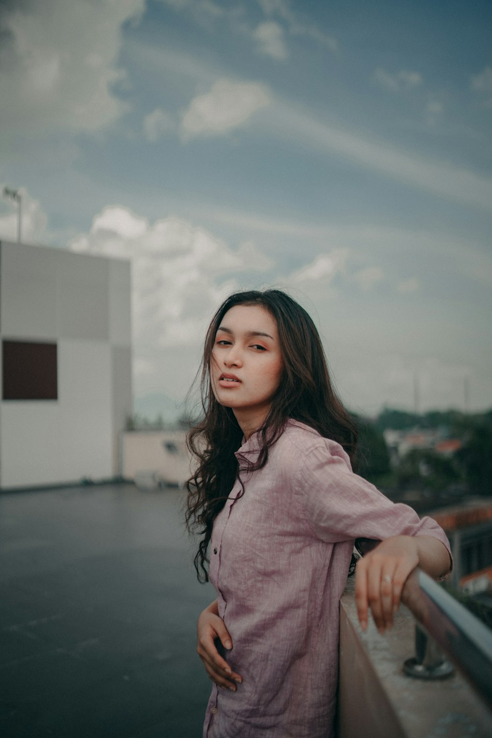 a woman standing on top of a balcony next to a building