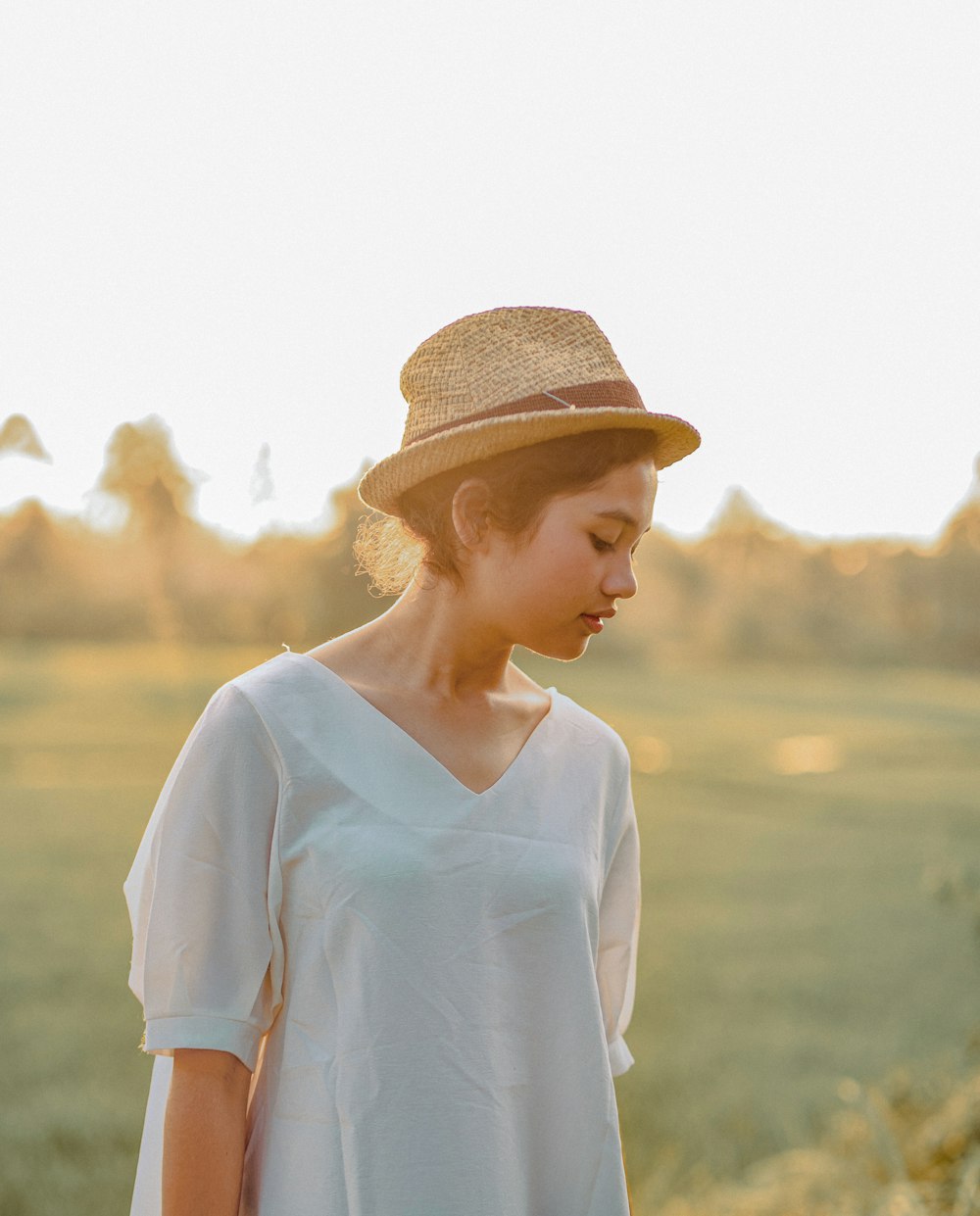 eine Frau, die auf einem Feld steht und einen Hut trägt