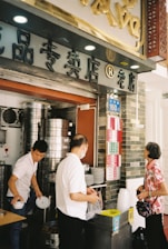A busy restaurant kitchen with staff preparing Asian and mainstream dishes efficiently.