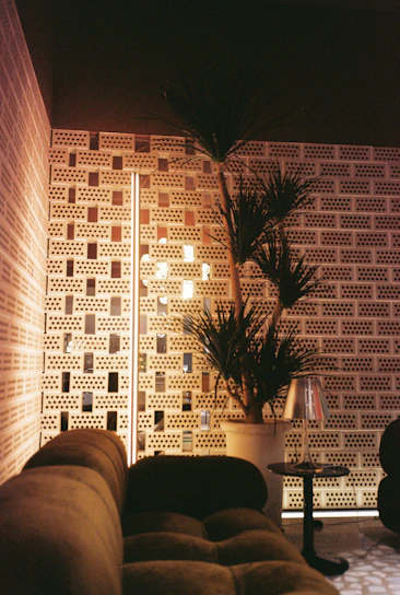 An elegant lounge area with textured cushions, a sculptural floor lamp, and a rich wood accent wall.