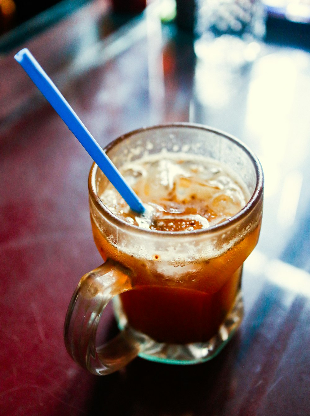 a glass of iced tea with a blue straw