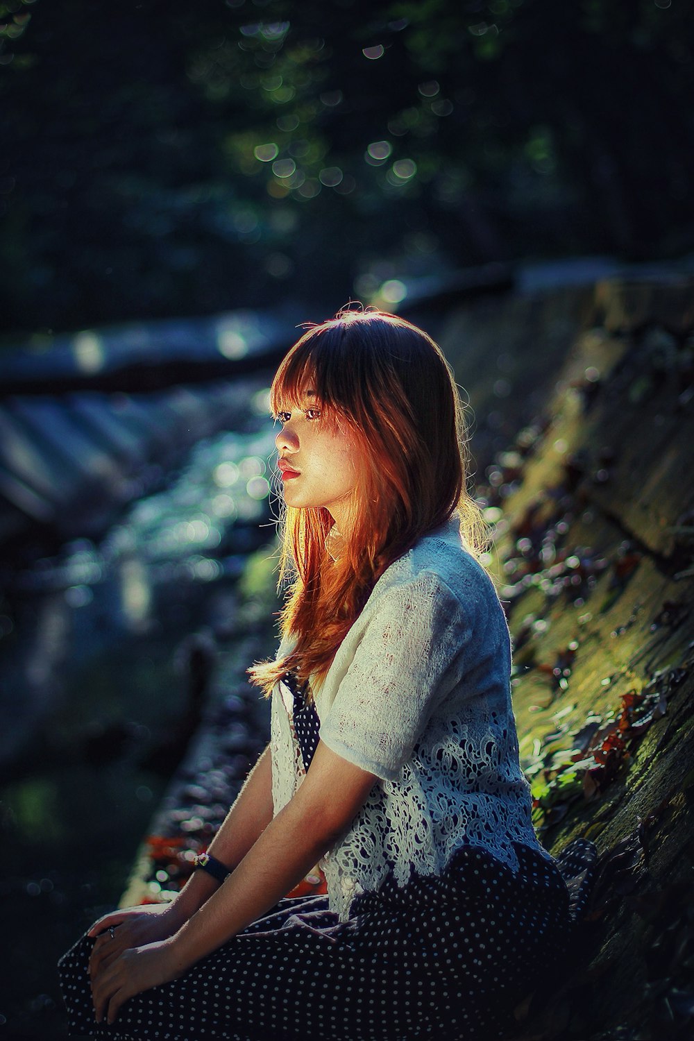 a woman sitting on a rock next to a river