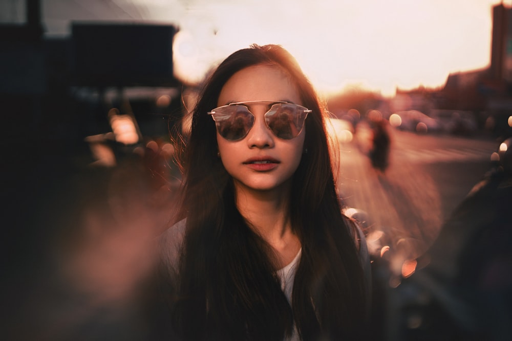 a woman wearing sunglasses standing on the side of a road