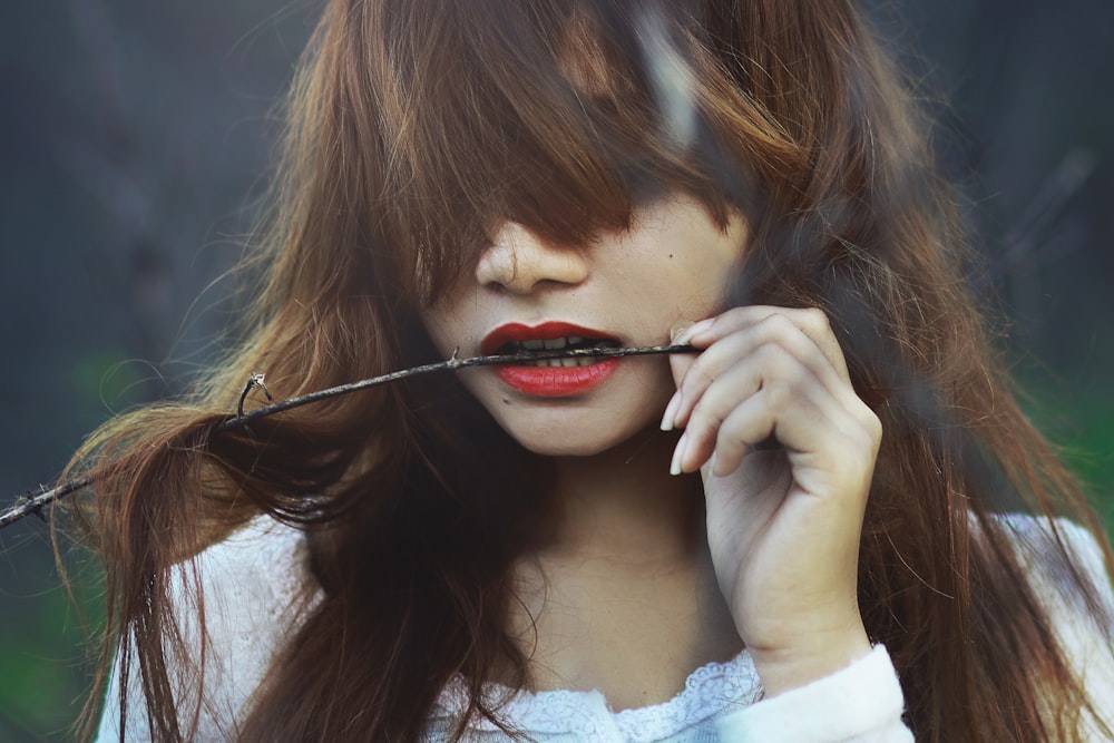 a woman with red lipstick holding a long black stick