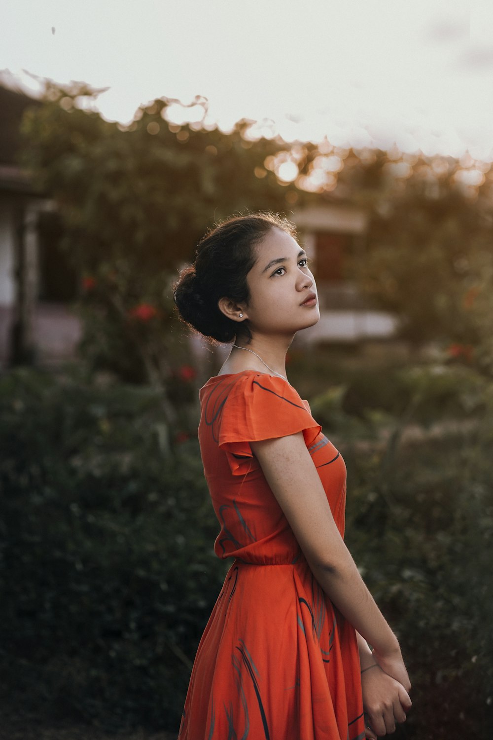 a woman in an orange dress standing in a field