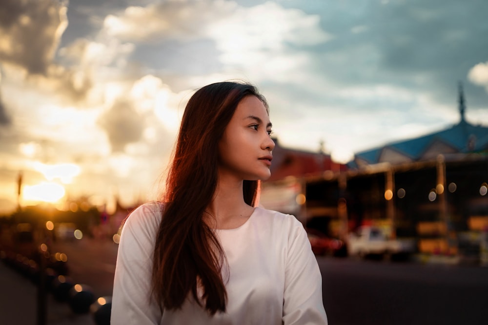 a woman standing on a street with a cloudy sky in the background