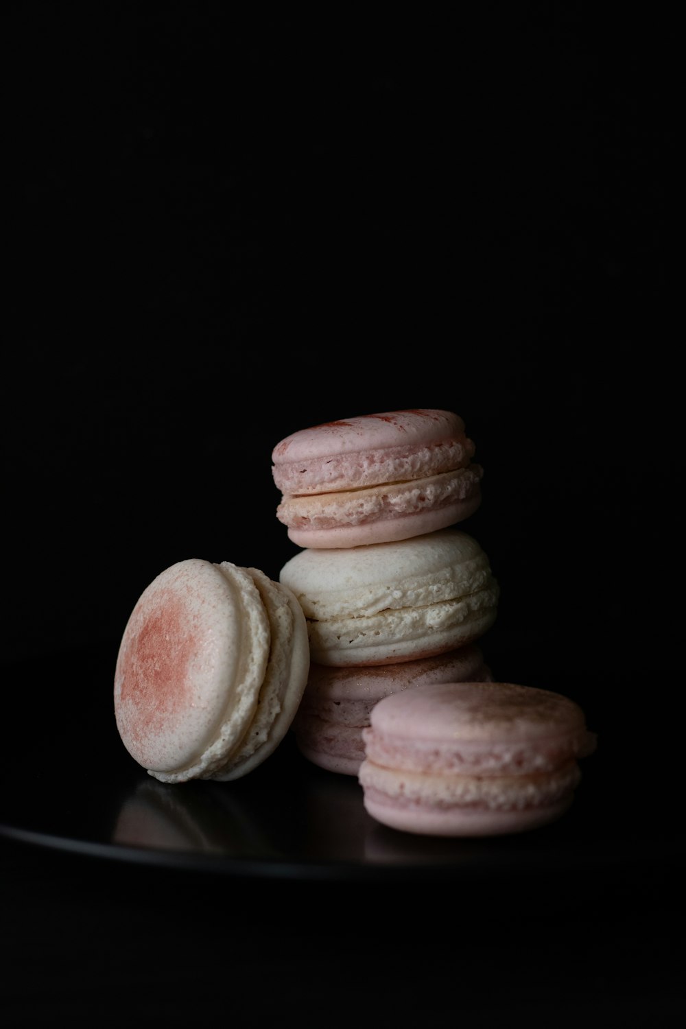 a black plate topped with pink and white macaroons