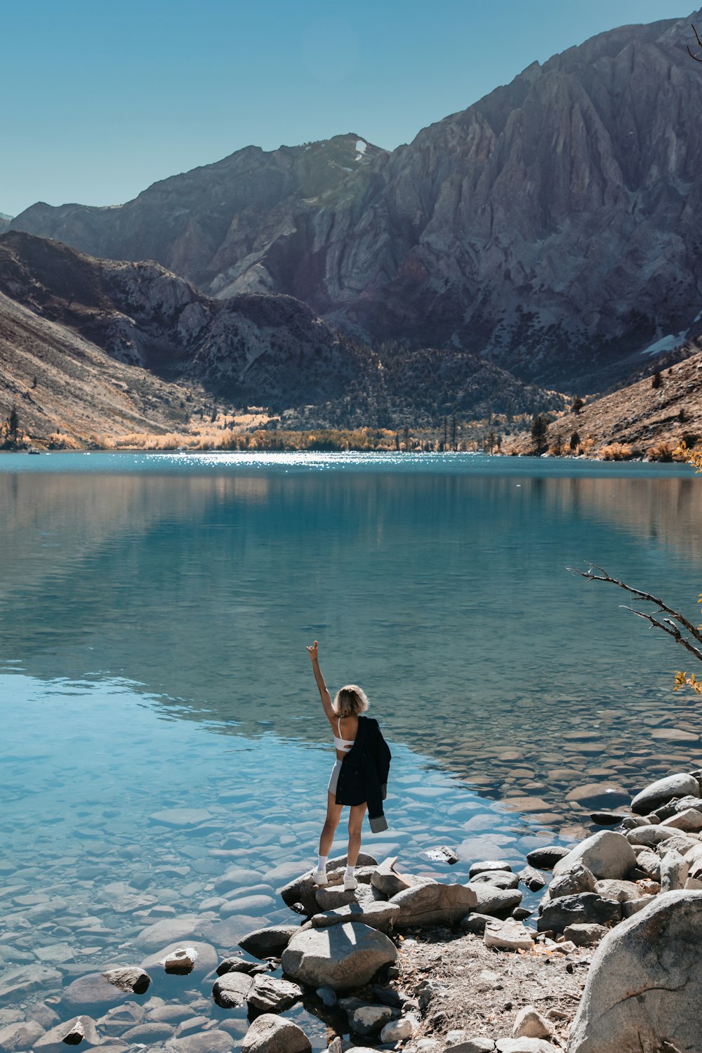 a young boy standing on rocks near a body of water