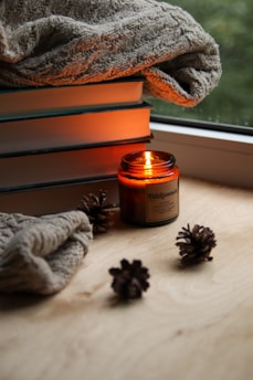 A cozy scene with a book, candle, and snacks from a lifestyle subscription box.