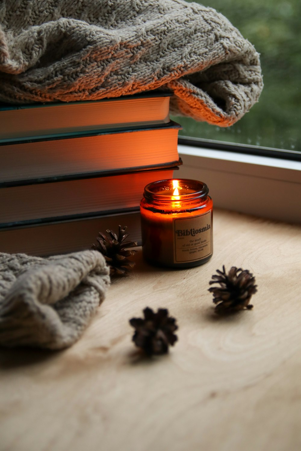 a candle sitting on top of a wooden table next to a window