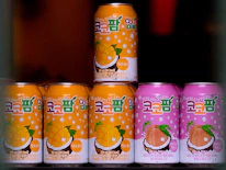 Bright, colorful arrangement of Enforcer Coco bottles in mango, orange, grape, lychee, and strawberry flavors on a white background.