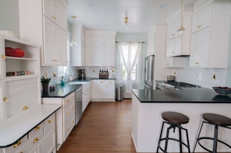 a kitchen with white cabinets and black counter tops