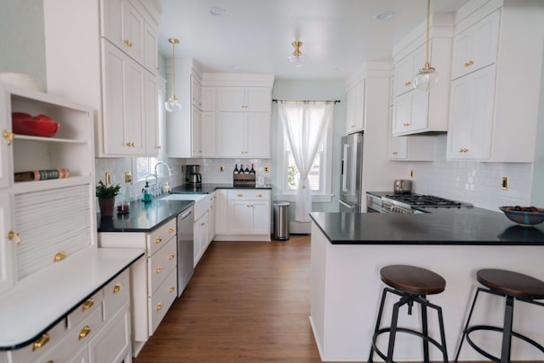 a kitchen with white cabinets and black counter tops