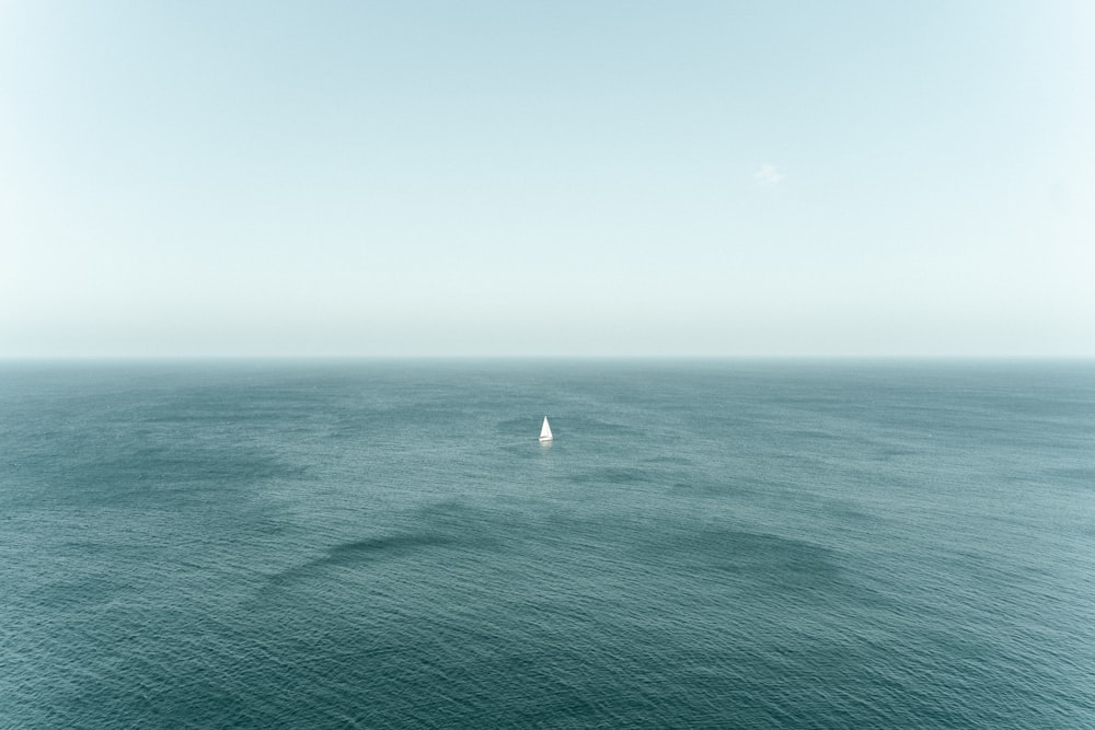 a lone sailboat in the middle of the ocean