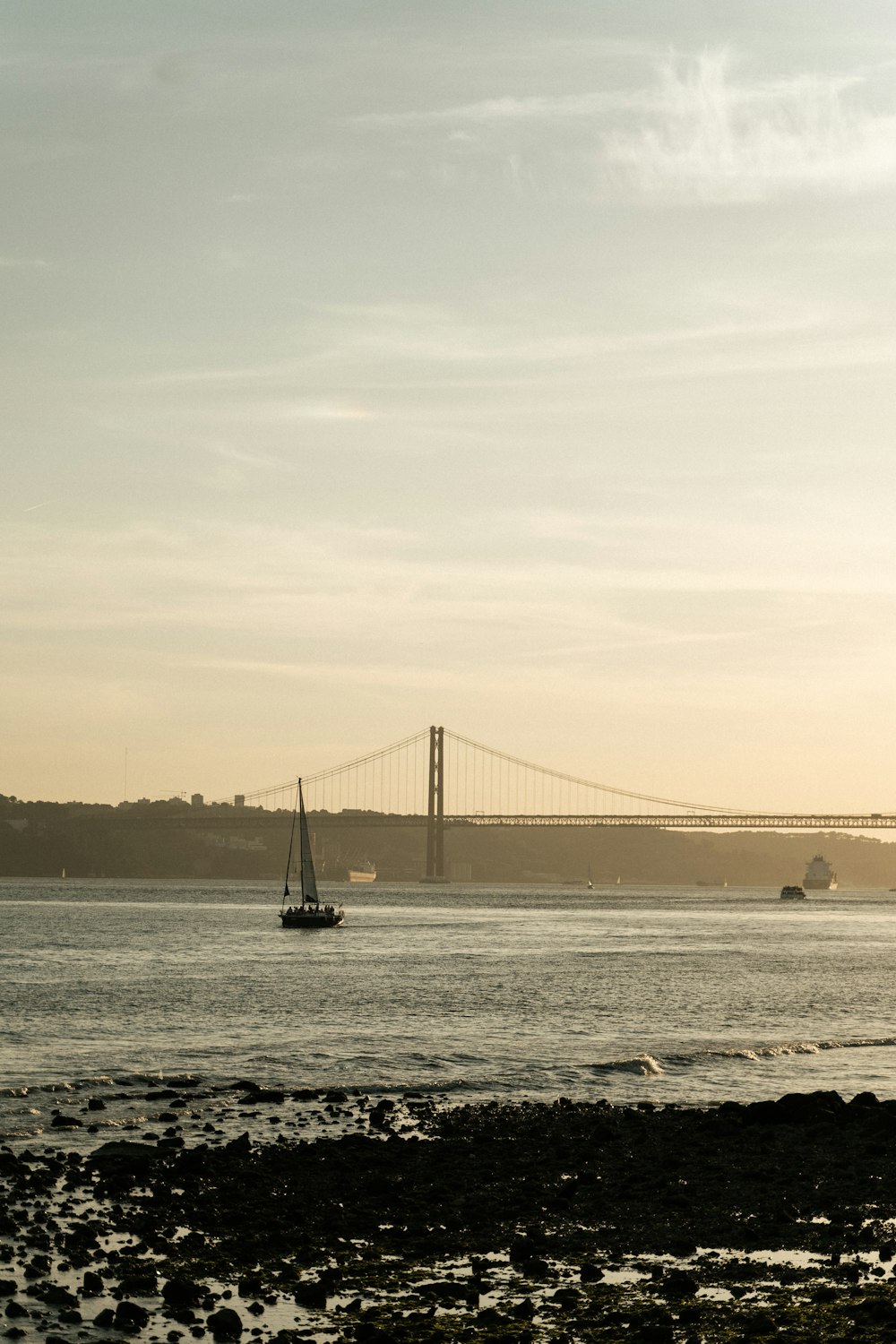 a sailboat on a body of water near a bridge