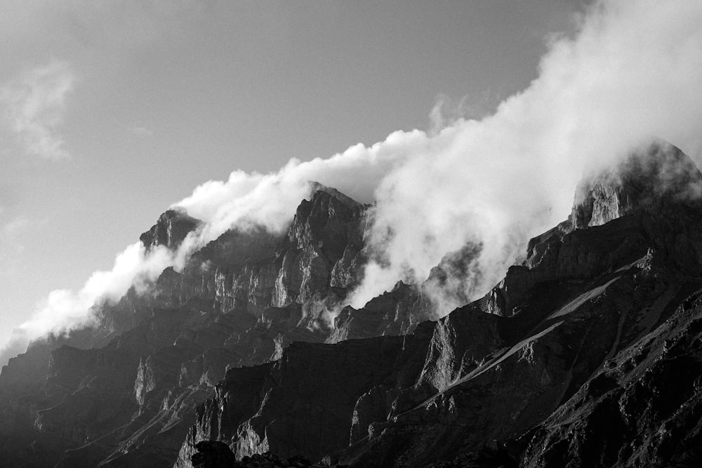 a black and white photo of a mountain covered in clouds