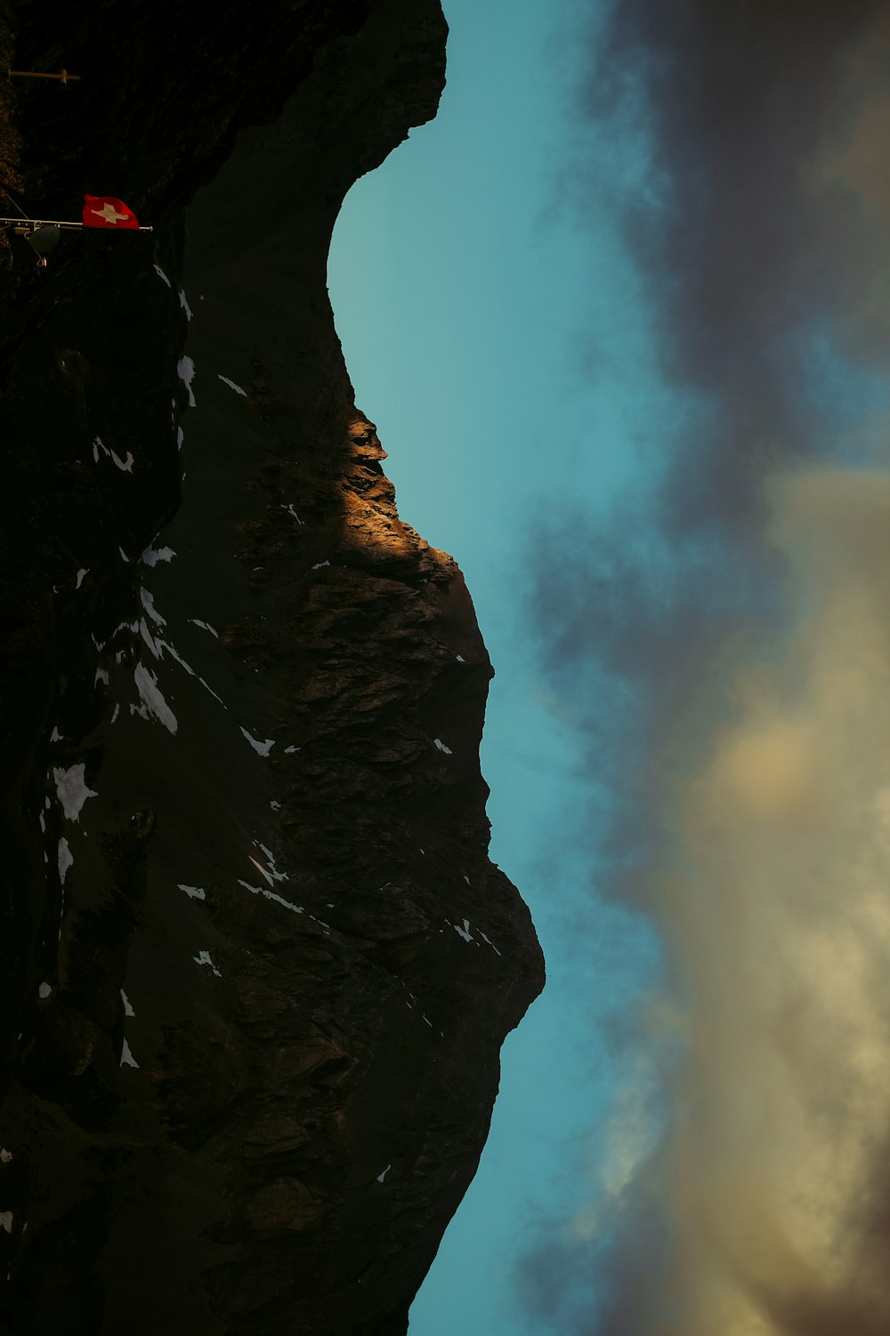 a plane flying over a mountain side under a cloudy sky