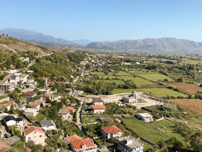 A panoramic view of village houses with green fields in the background.