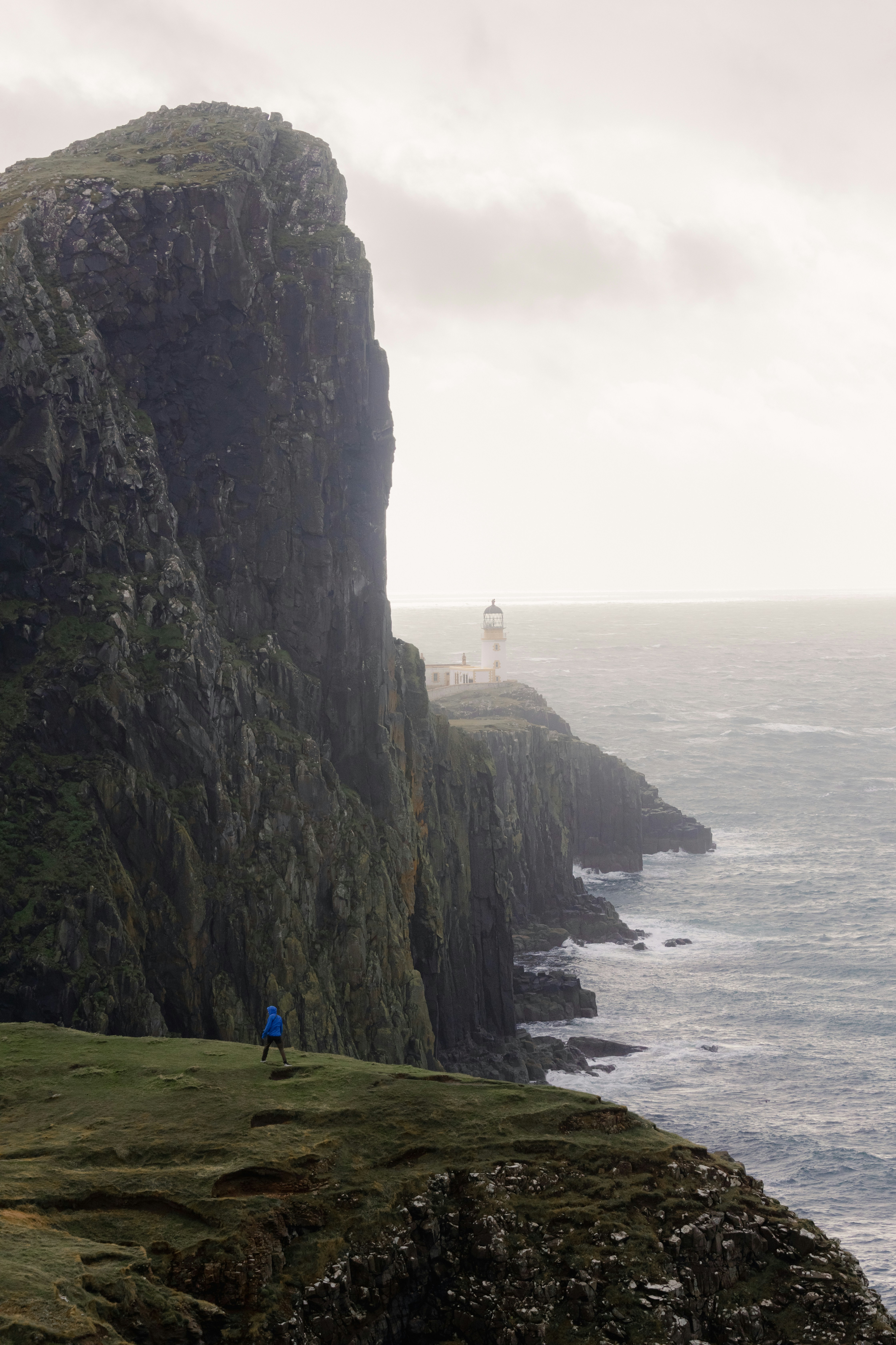 A person standing on the edge of a cliff near the ocean