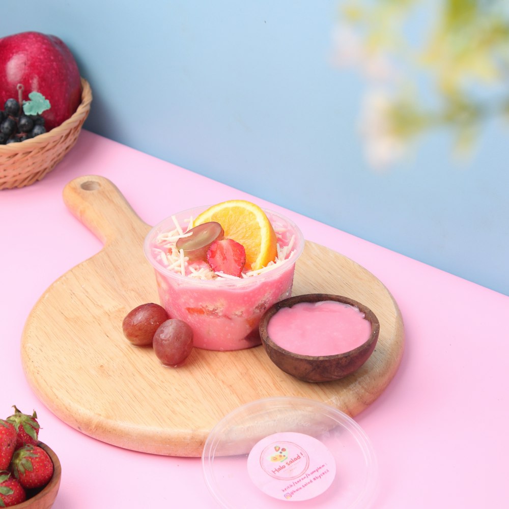 a wooden cutting board topped with a bowl of fruit