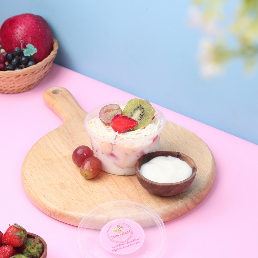 a table topped with a bowl of fruit and a bowl of yogurt