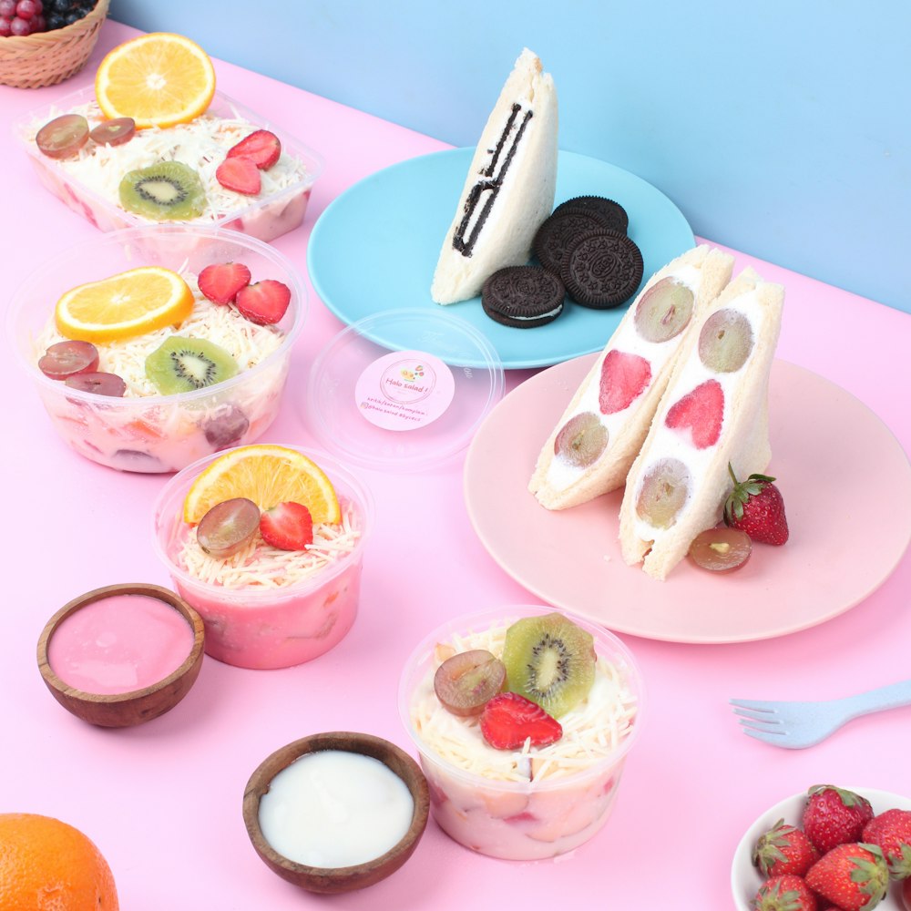 a pink table topped with desserts and fruit