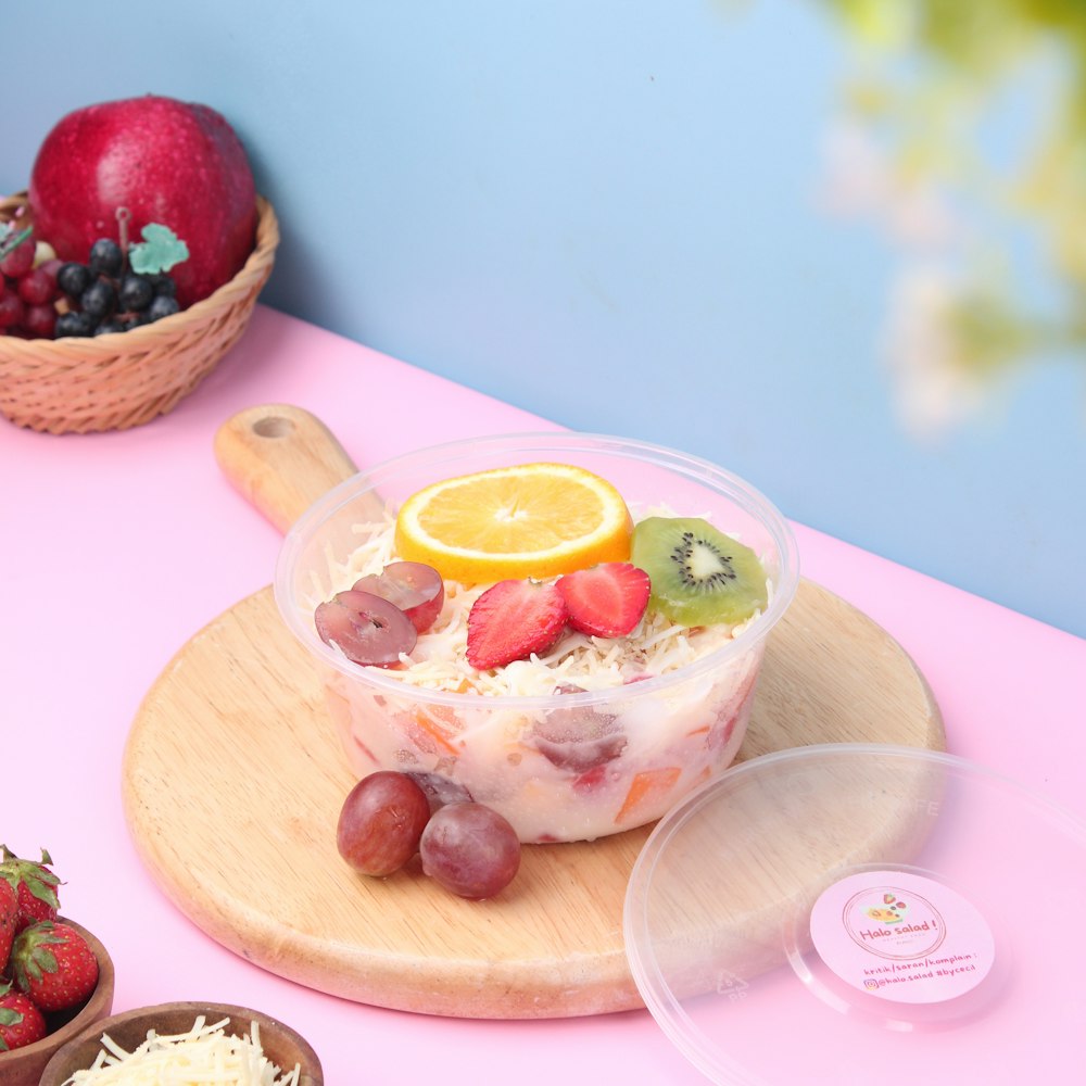 a bowl of fruit is sitting on a cutting board