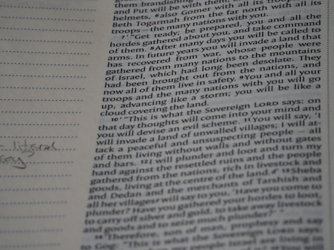 A close-up photograph of a page from a book, likely a religious text, featuring dense printed text on the right side. The left margin contains lined spaces for notes, where a few handwritten words are visible. The text includes a passage with verses speaking about future events and prophecies.