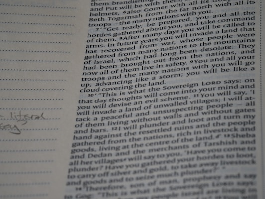 A close-up photograph of a page from a book, likely a religious text, featuring dense printed text on the right side. The left margin contains lined spaces for notes, where a few handwritten words are visible. The text includes a passage with verses speaking about future events and prophecies.