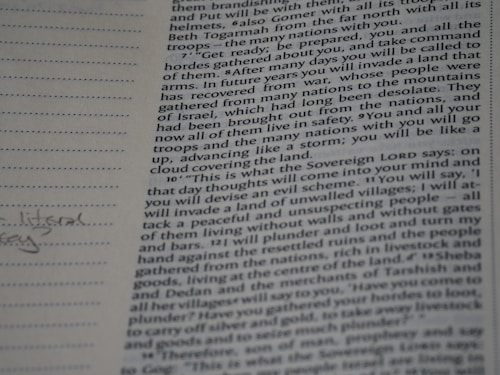 A close-up photograph of a page from a book, likely a religious text, featuring dense printed text on the right side. The left margin contains lined spaces for notes, where a few handwritten words are visible. The text includes a passage with verses speaking about future events and prophecies.