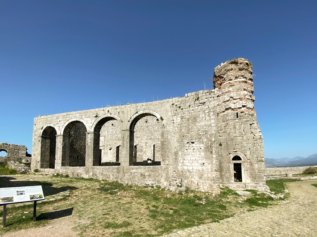 a stone building with arches and a bench in front of it