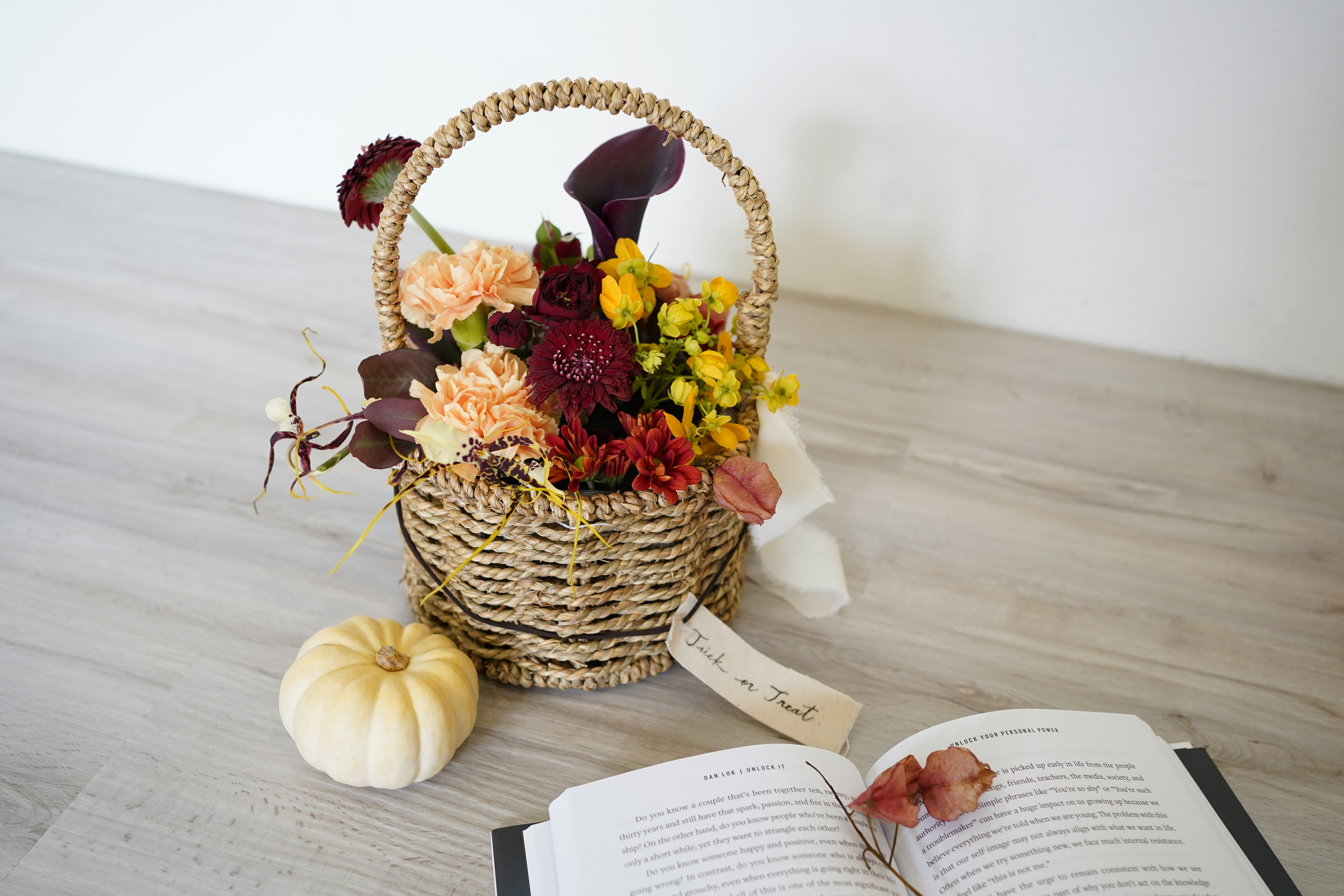 a basket of flowers next to an open book
