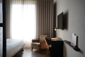 A modern, sunlit studio room with minimalist decor and cozy furnishings.
