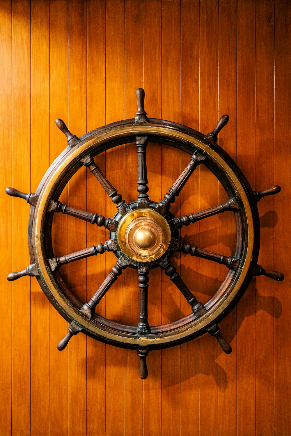 a ship's steering wheel mounted on a wooden wall