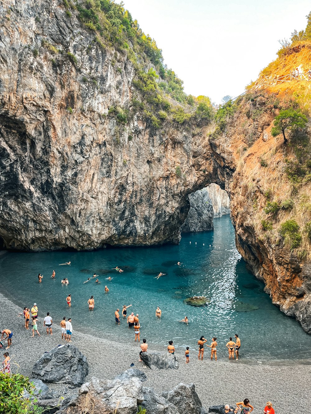 a group of people standing on a beach next to a body of water