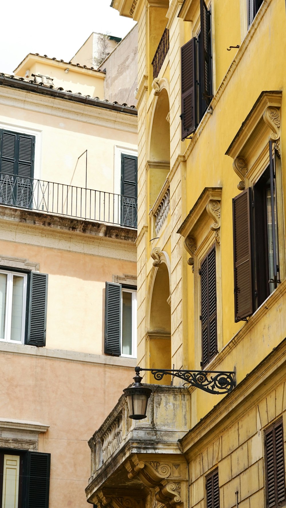 a yellow building with black shutters and balconies